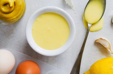 Beyaz bir kasede açık gri arka planda malzemelerle kokulu sarımsak sosu. Salata, et, balık ve sebzeler için Akdeniz sosu. Yatay oryantasyon. Üst görünüm