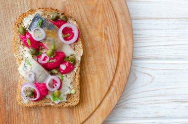 Geleneksel İskandinav usulü salamura ringa balığı, parlak pancar kreması, ince kırmızı soğan halkaları, kapari. Açık sandviç ve uyumlu renk kombinasyonu. Üst görünüm