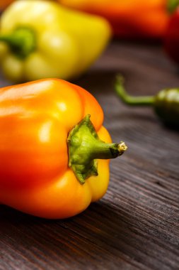 Koyu ahşap yüzey üzerinde yeşil saplı Bulgar turuncu biber