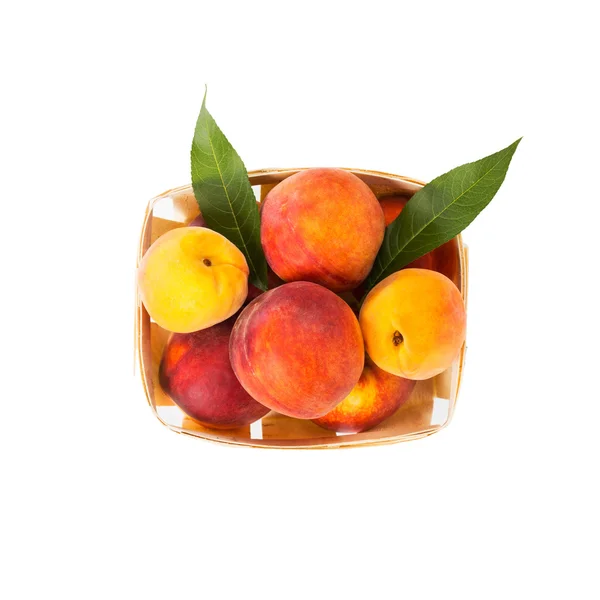 Свежие вкусные персики с зелеными листьями в деревянной коробке - изолированные на белом фоне — стоковое фото
