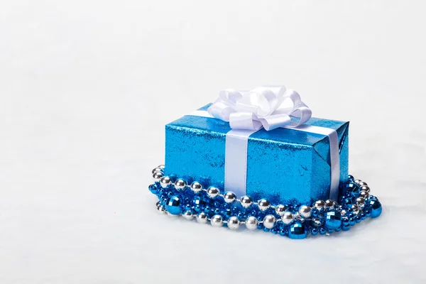 Parlak gümüş şerit ve beyaz zemin üzerine boncuk mavi Noel hediye kutusu