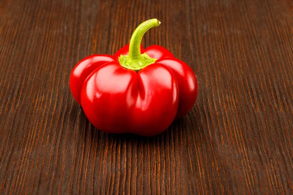 Koyu ahşap yüzey üzerinde yeşil saplı kırmızı biber