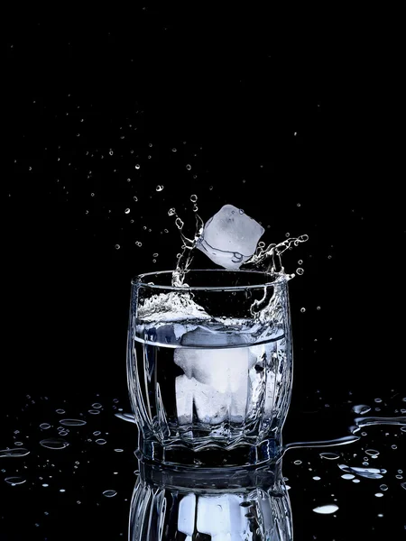 Splash water out of a glass with ice — Stock Photo, Image