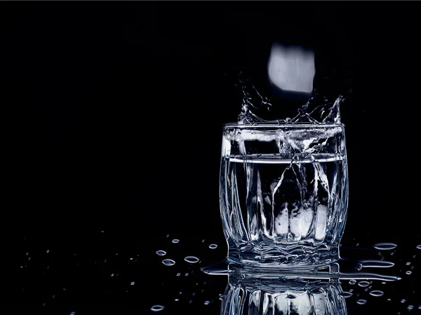 Splash water out of a glass with ice — Stock Photo, Image