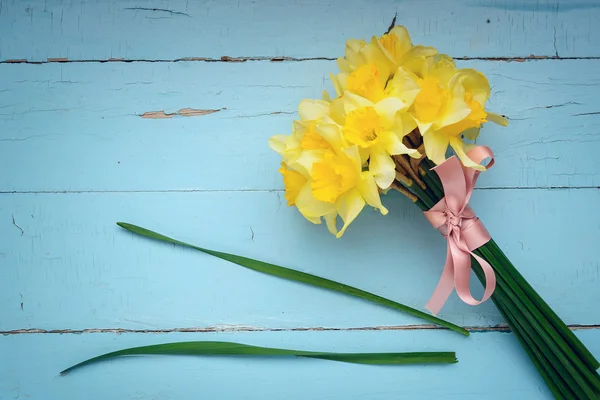 Buquê de narcisos deitado em uma mesa rústica — Fotografia de Stock