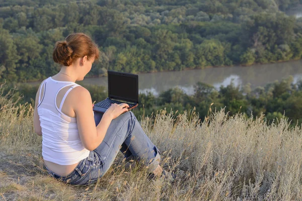 Chica con un ordenador en la naturaleza —  Fotos de Stock