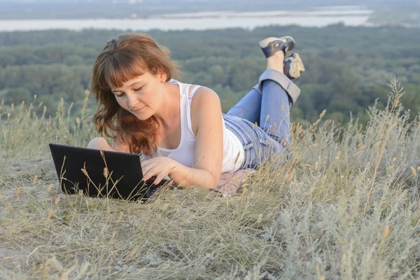 Chica con un ordenador en la naturaleza — Foto de Stock