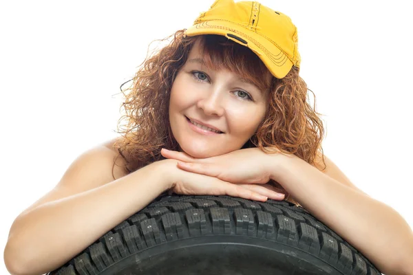 Girl in overalls and a baseball cap keeps car tire — Stock Photo, Image