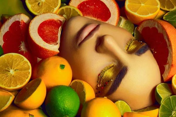 Model lies among many citrus fruits.