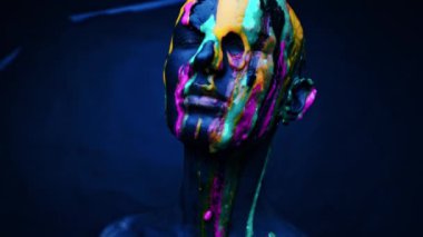 Genç adam floresan boyayla boyanmış. Yüzü ve kaslı.