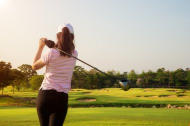 Asyalı kadın golfçü süpürme golf sahası yaz aylarında vurdu.