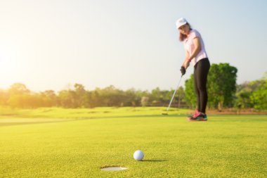 Asyalı kadın golf tatil sırasında kuş için yeşil koyarak