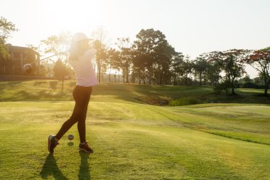 Asyalı kadın golfçü süpürme golf sahası yaz aylarında vurdu.