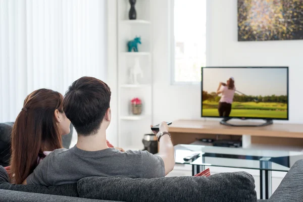 Jovem casal asiático waching golfe esporte na tv em casa — Fotografia de Stock