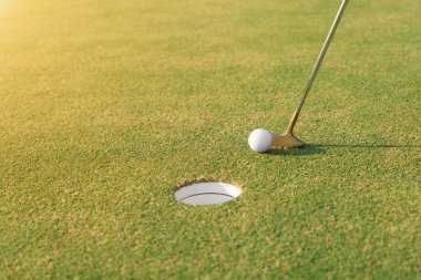 Golf oyuncu yeşil koyarak bir deliğe golf topu vurmak. 