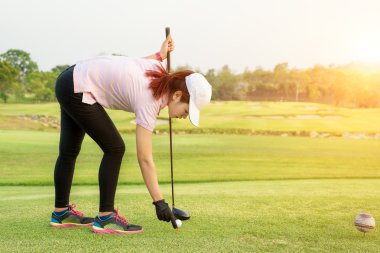 Asyalı kadın Golf topu tee için zaten golf oynamak için koyarak. Gol