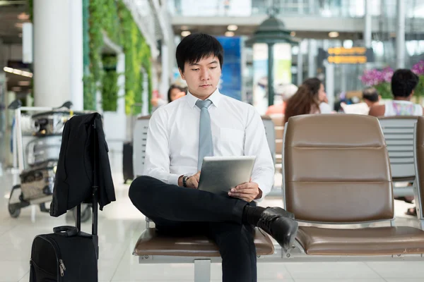 Asiatique homme d'affaires en utilisant tablette numérique tout en attendant dans le salon un — Photo