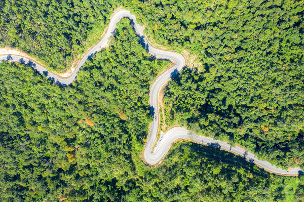 Aerial view over mountain road going through tropical rainforest landscape in Thailand