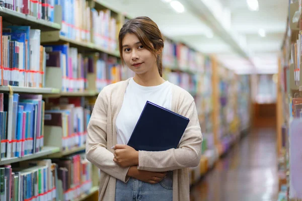 Portret Studentki Inteligentnej Azji Czytającej Książki Patrzącej Kamerę Między Regałami — Zdjęcie stockowe