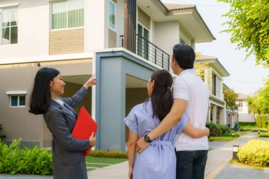 Asyalı emlakçı kadın dosyasında ev detaylarını genç Asyalı çift aşığına gösteriyor ve satın almak istiyor. Yeni bir ev alıyorum.