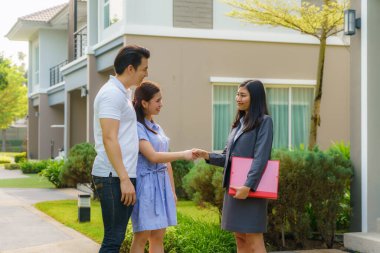 Yeni evlerini arayan mutlu Asyalı çift bir anlaşmadan sonra emlakçıyla tokalaşıyor. Ev almak için kontrat imzaladıktan sonra genç çiftler el sıkışıyor.