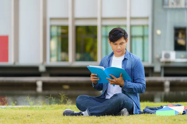 亚洲大学生在校园草地上快乐地坐着 在公园看书的画像 — 图库照片