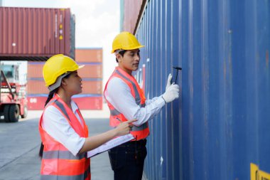 Asyalı mühendis ya da ustabaşı, konteynırı kontrol etmek için Çip Çekici aracını kullanır. onarım tamamlandıktan sonra müşteriye teslimatı hazırlamak için.