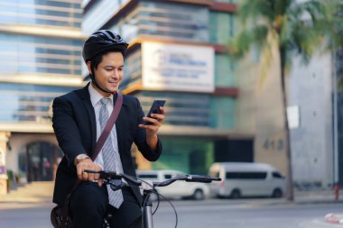 Asyalı işadamı cep telefonlarını uygulamaları, haritaları ve sabah işe gidiş yönlerini görmek için kullanıyor.
