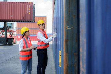 Asyalı mühendis ya da ustabaşı, konteynırı kontrol etmek için Çip Çekici aracını kullanır. onarım tamamlandıktan sonra müşteriye teslimatı hazırlamak için.