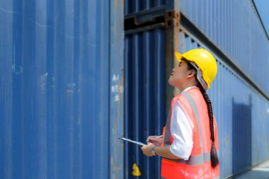Asyalı işçi kadın teslimatı hazırlamak için onarım tamamlandıktan sonra konteynırı kontrol ediyor..