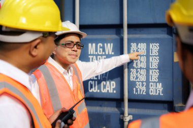 Asyalı ustabaşı, yeni denetleme konteynırı işçilerine çeşitli konteynır bileşenleri için yeni eğitim çalışanlarını anlatıyor ve öğretiyor..