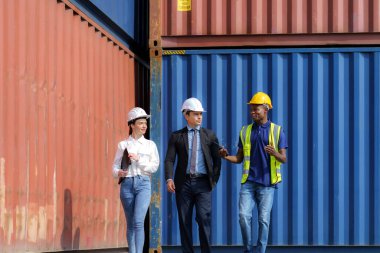 Afro-Amerikan ustabaşı konteynır deposunun çeşitli kısımlarını yanında kadın bir sekreterle birlikte beyaz bir erkek yöneticiye anlatıyor..