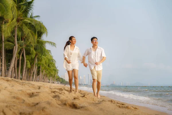 アジアのカップルは タイの夏の休暇中にヤシの木とビーチビーチの海で走り 手をつないでいます — ストック写真