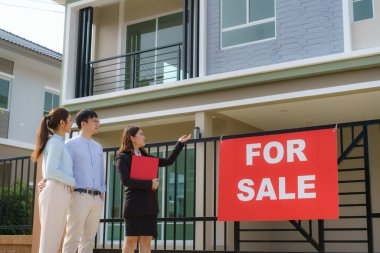 Asyalı emlakçı kadın dosyasında ev detaylarını genç Asyalı çift aşığına gösteriyor ve satın almak istiyor. Yeni bir ev alıyorum.