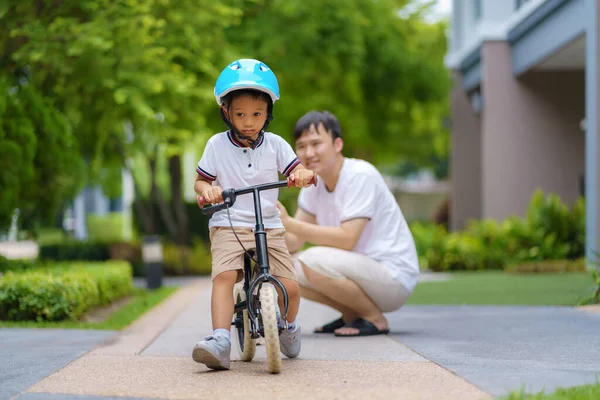 アジアの父は近所の庭で自転車に乗る方法を子供に教えています — ストック写真