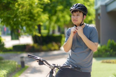 Kask takan Asyalı bir adam hem fiziksel hem de zihinsel sağlık için mahallesinde bisiklet sürmeye hazırlanıyor..