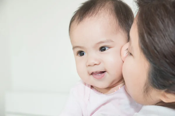 Feliz familia alegre. Asiática madre y bebé besos, riendo un — Foto de Stock