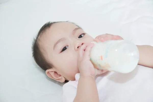 Asian pretty baby girl drinking milk in bed — Stock Photo, Image