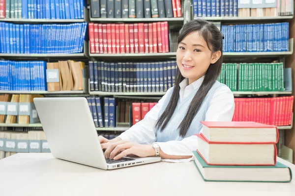 Asyalı öğrenci üniversite kitaplığında dizüstü bilgisayar kullanarak — Stok fotoğraf