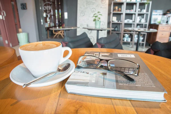 Taza de café con cristalería en el libro en la mesa —  Fotos de Stock