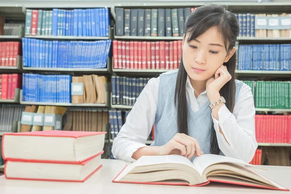 Estudiante asiático con libro abierto leyéndolo en la biblioteca universitaria — Foto de Stock