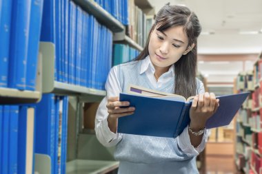 Asyalı öğrenci Üniversitesi kitaplığındaki kitap okumak