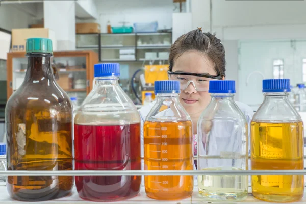 Nahaufnahme einer schönen asiatischen Wissenschaftlerin, die eine Chemieflasche betrachtet — Stockfoto