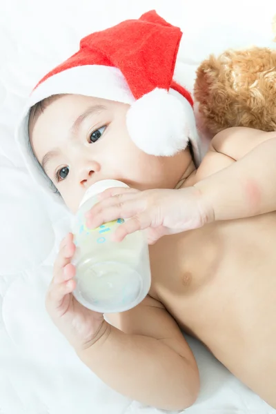 Asian baby with christmas cap eating milk from bottle — Stock Photo, Image