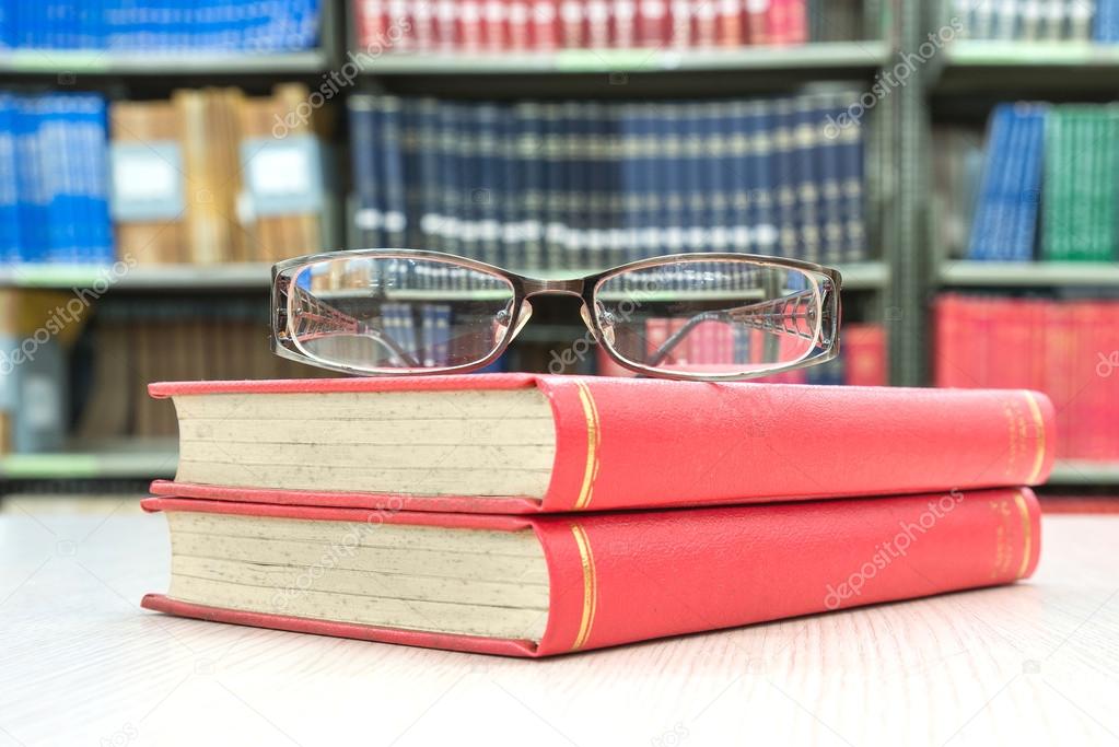 book and glasses on table in library