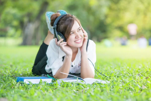 Asian student with Headphones Outdoors. Enjoying Music