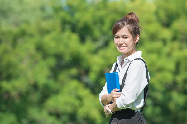 Estudiante al aire libre sosteniendo un cuaderno y sonriendo — Foto de Stock