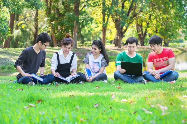 Šťastný skupina studentů, sedět u parku mluví — Stock fotografie