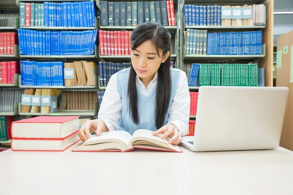 Student with open book reading it in college library — Stock Photo, Image