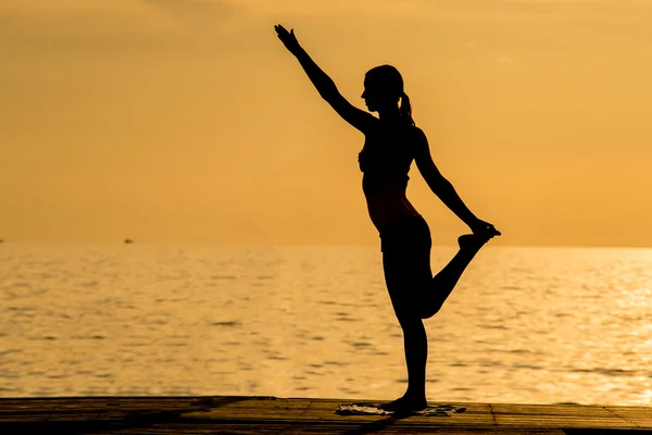 Силуэт женщины, делающей йогу на пляже — стоковое фото